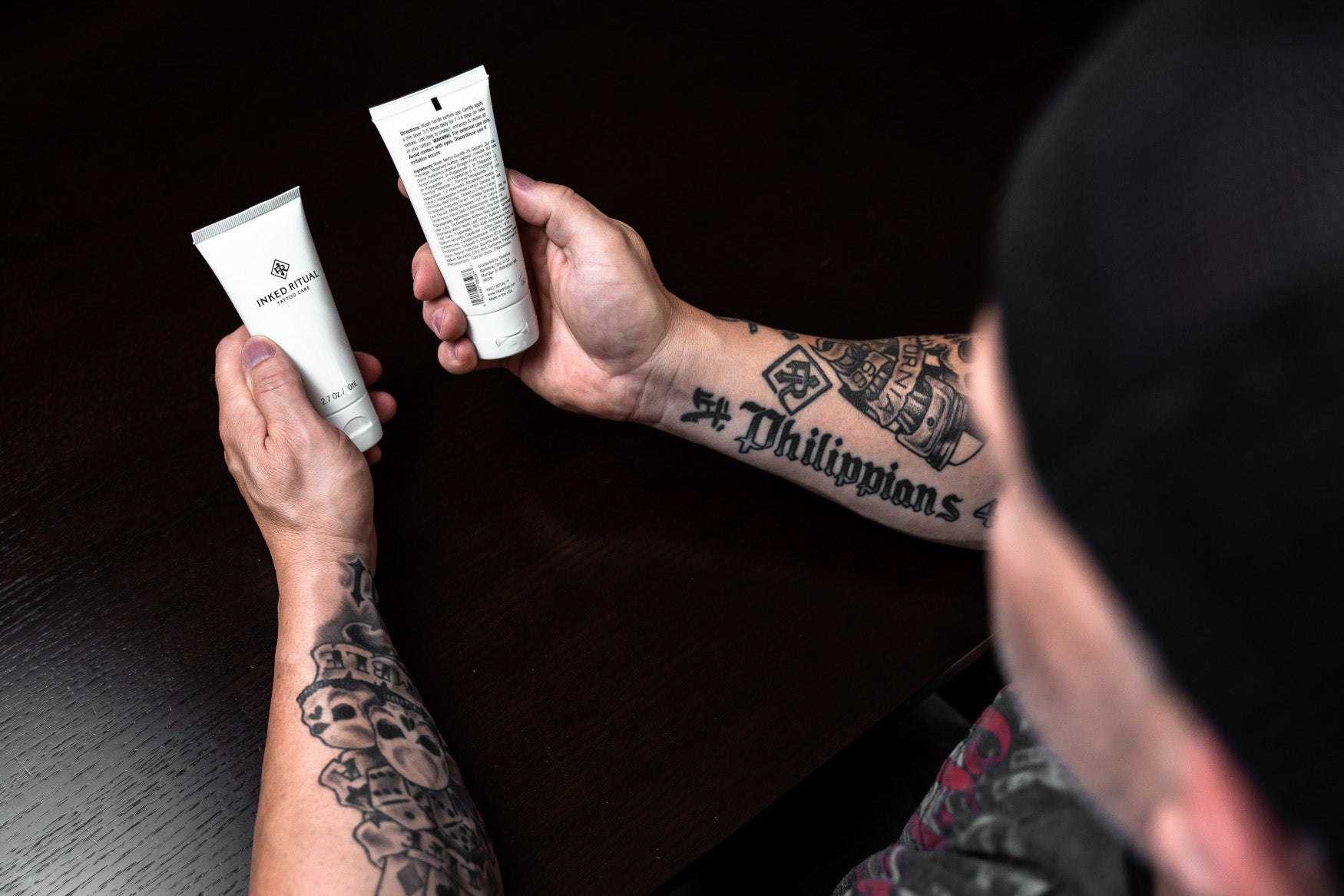 Man with Tattooed Forearms Holding two Inked Ritual Tattoo Care Serum Philippians 4:13 Tattoo